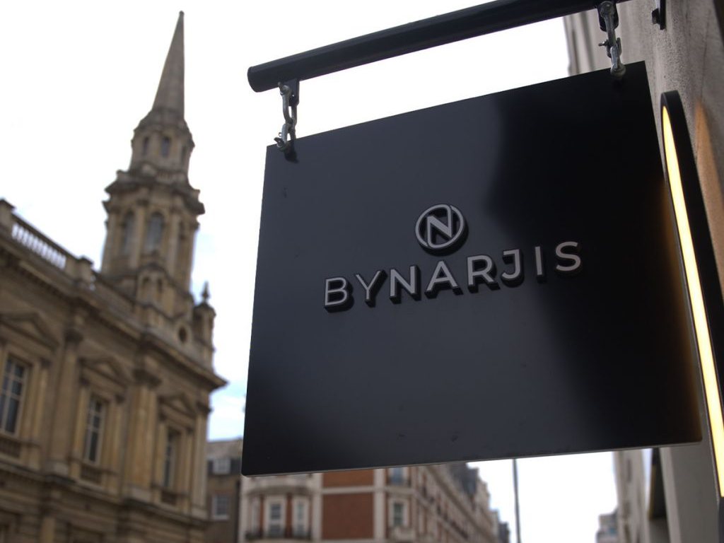 The By Narjis sign hanging over Thayer Street, with a church spire behind it